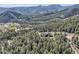 Panoramic aerial shot showcases log home surrounded by lush mountain forests at 10450 Hondah Dr, Littleton, CO 80127