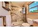 Modern bathroom featuring tile shower, glass door, shelving, and a scenic window view at 10450 Hondah Dr, Littleton, CO 80127