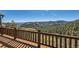 Inviting deck with wooden railing overlooking a stunning mountain and forest landscape at 10450 Hondah Dr, Littleton, CO 80127