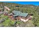 Scenic aerial view of log home with a large deck, green roof and beautiful landscaping at 10450 Hondah Dr, Littleton, CO 80127