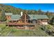 Sprawling log cabin with an attached sunroom surrounded by green trees at 10450 Hondah Dr, Littleton, CO 80127