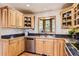 Well-lit kitchen features wood cabinets, black countertops, and a bay window overlooking trees at 10450 Hondah Dr, Littleton, CO 80127