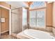Bright bathroom features a glass shower and separate soaking tub with a large picture window at 9875 Greensview Cir, Lone Tree, CO 80124