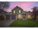 Charming two-story home featuring a well-manicured lawn and a three-car garage, bathed in the glow of a vibrant twilight sky at 527 Stonemont Dr, Castle Pines, CO 80108
