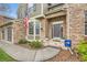 Inviting entrance with well-kept landscaping, a brick facade, a three-car garage, and patriotic decor at 527 Stonemont Dr, Castle Pines, CO 80108