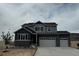 Two-story home with gray siding, a two-car garage, and a well-manicured lawn on a cloudy day at 13960 Hanging Lake St, Parker, CO 80138