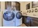 Well-organized laundry room with modern washer and dryer, ample cabinet space, and counterspace at 13960 Hanging Lake St, Parker, CO 80138