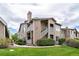 Exterior shot of the condo with a green lawn, walkway, and mature bushes that adds to its curb appeal at 3845 Canyon Ranch Rd # 102, Highlands Ranch, CO 80126