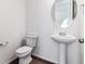 Clean, minimalist powder room featuring a pedestal sink, round mirror, and modern fixtures at 9165 Truckee Ct, Commerce City, CO 80022