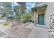 Charming entrance with a green door surrounded by professionally landscaped yard and a short stepped walkway at 31112 Black Eagle Dr # 101, Evergreen, CO 80439