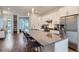 Open concept kitchen with white cabinetry, a large island with seating, stainless appliances at 4728 S Acoma St, Englewood, CO 80110