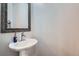 Stylish powder room with a pedestal sink, decorative mirror, and neutral paint at 4728 S Acoma St, Englewood, CO 80110