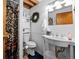 Cozy bathroom featuring wainscoting, toilet, sink, floral shower curtain, exposed plumbing, and a decorative wreath at 59 S De Gaulle St, Aurora, CO 80018
