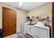 Well-equipped laundry room with a sink, washer, dryer, storage shelf, and access door at 59 S De Gaulle St, Aurora, CO 80018