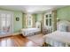 Spacious bedroom with twin beds, hardwood floors, bright green walls, and large windows at 199 Lafayette St, Denver, CO 80218