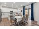Modern kitchen with stainless steel appliances, white cabinetry, island seating, and an adjacent dining area at 656 N Bersshine St, Watkins, CO 80137
