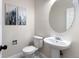 Clean powder bathroom features modern pedestal sink, round mirror, and decorative wall art at 2089 Meadow Sweet Ln, Erie, CO 80516