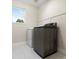 Bright laundry room with stainless steel washer and white dryer under window and tile flooring at 2089 Meadow Sweet Ln, Erie, CO 80516