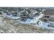 Aerial view showcases the house, yard, stone patio with firepit, and deck, nestled in a snow-covered neighborhood at 15842 Willow St, Thornton, CO 80602