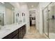 Modern bathroom with dual sinks, quartz countertop, a glass-enclosed shower, and a walk-in closet at 15842 Willow St, Thornton, CO 80602