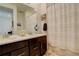 Bathroom featuring double sink vanity with dark cabinets, a large mirror and shower with a white curtain at 15842 Willow St, Thornton, CO 80602