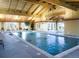 Indoor pool with a vaulted ceiling, natural wood beams, and ample natural light from large windows at 15842 Willow St, Thornton, CO 80602
