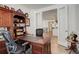 Well-appointed office featuring built-in shelving, a large desk, and an open view into the living space at 15842 Willow St, Thornton, CO 80602
