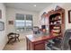 Inviting home office with built-in wooden desk and shelving, and bright natural light from the window at 15842 Willow St, Thornton, CO 80602