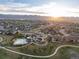 Aerial view of a community featuring a pool, clubhouse and housing, set against a mountain backdrop at sunset at 8354 Big Thompson St, Littleton, CO 80125