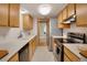 Kitchen with wooden cabinets, white counter tops, stainless steel appliances and view into bedroom at 2525 S Dayton Way # 1514, Denver, CO 80231