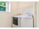 Functional laundry room with a washer, dryer, overhead shelving, and a window for natural light and ventilation at 5895 Biscay St # D, Denver, CO 80249