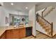 Well-lit kitchen featuring granite countertops, stainless sink, wooden cabinetry, and adjacent carpeted staircase at 2972 W Long Dr # C, Littleton, CO 80120