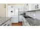 White kitchen with granite countertops and stainless steel appliances at 5593 S Himalaya Way, Centennial, CO 80015