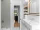 Updated bathroom with a modern sink, chrome fixtures, and open shelving, leading to a bright hallway at 3222 S Fairfax St, Denver, CO 80222