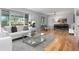 Bright living room featuring hardwood floors, a modern glass coffee table, and large windows overlooking the backyard at 3222 S Fairfax St, Denver, CO 80222