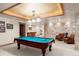 Finished basement with a pool table and a stone accent wall with brown leather seating and a coffered ceiling at 4 Redhawk Run, Englewood, CO 80113