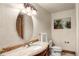 Powder room with decorative mirror, vanity with marble countertop, and ornate sconce lighting at 4 Redhawk Run, Englewood, CO 80113