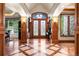 Elegant foyer featuring hardwood floors with decorative inlays, wood trim, and stained glass double doors at 4 Redhawk Run, Englewood, CO 80113