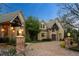 Charming stone home featuring a circular driveway with mature landscaping and unique architectural details at 4 Redhawk Run, Englewood, CO 80113