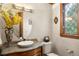 Cozy powder room featuring a unique sink, granite countertop, decorative mirror, and a leaded glass window at 4 Redhawk Run, Englewood, CO 80113