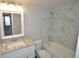 Bright bathroom features marble-look tile, soaking tub, and vanity with marble-look countertop at 11937 E Harvard Ave # 101, Aurora, CO 80014