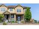 Attractive tan townhouse features a stone facade, covered front porch, and well-manicured landscaping at 23293 E Jamison Dr, Aurora, CO 80016