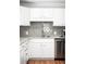 Updated kitchen showcasing white cabinets, granite countertops, a stylish backsplash, and stainless steel appliances at 1757 S Elm St, Denver, CO 80222