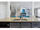 Granite topped kitchen island features a sink and faucet. Open concept view to living room and staircase at 4915 Sage Brush Dr, Broomfield, CO 80023