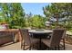 Outdoor dining space with seating around a table and grill surrounded by green trees and blue sky at 4915 Sage Brush Dr, Broomfield, CO 80023
