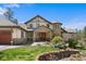Elegant home with stone accents, a portico over the entrance, and a well-manicured front lawn at 10231 Democrat Rd, Parker, CO 80134