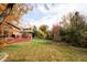 Lush backyard with mature trees, a large deck, and well-maintained lawn covered with fallen leaves at 1800 S Niagara Way, Denver, CO 80224