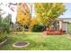 Scenic backyard with mature trees, a spacious lawn, a deck, and decorative landscaping features at 1800 S Niagara Way, Denver, CO 80224