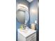 Stylish powder room featuring blue walls, round mirror, and elegant vanity with modern fixtures at 1800 S Niagara Way, Denver, CO 80224