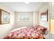 Cozy bedroom with a red quilt, window views, and built-in shelving for extra storage at 1800 S Niagara Way, Denver, CO 80224